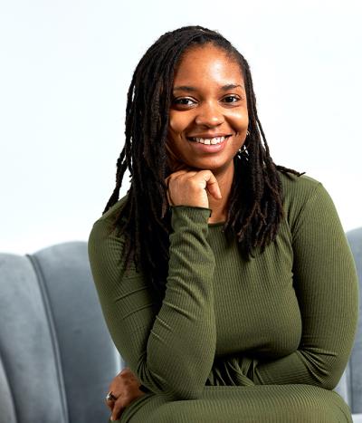jasmyne, sitting on a grey couch with a green shirt on 