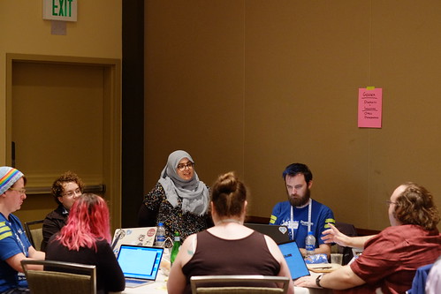 Diverse group of individuals sitting in front of laptops around a round table.